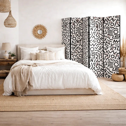 Chambre 
à coucher avec lit double, tapis en jute, paravent 
à motifs et miroir soleil en rotin